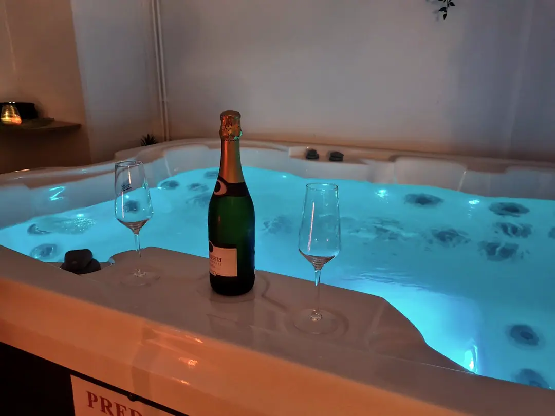 Osvetljen jacuzzi s steklenico penine in dvema kozarcema